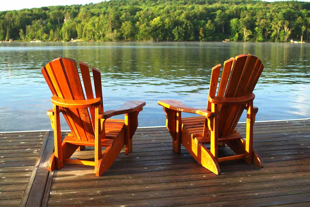 Deux chaises Adirondack orientés vers un lac