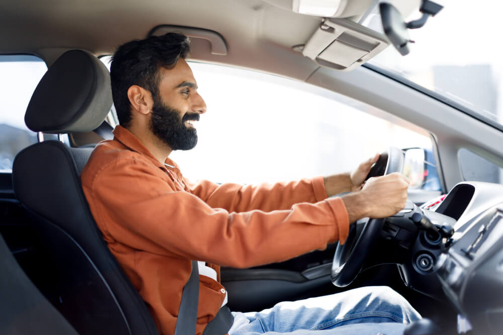 Heureux homme assis dans un véhicule, conduisant une nouvelle voiture