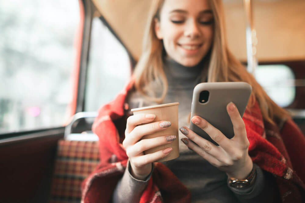 Woman using smartphone and holding coffee