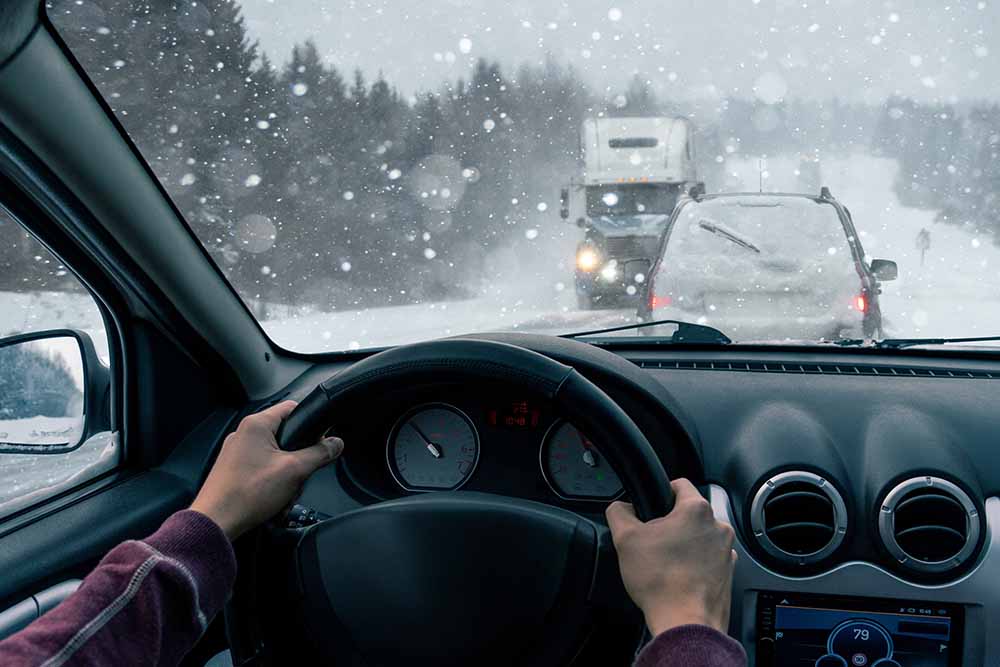 Un homme conduit une voiture dans un blizzard