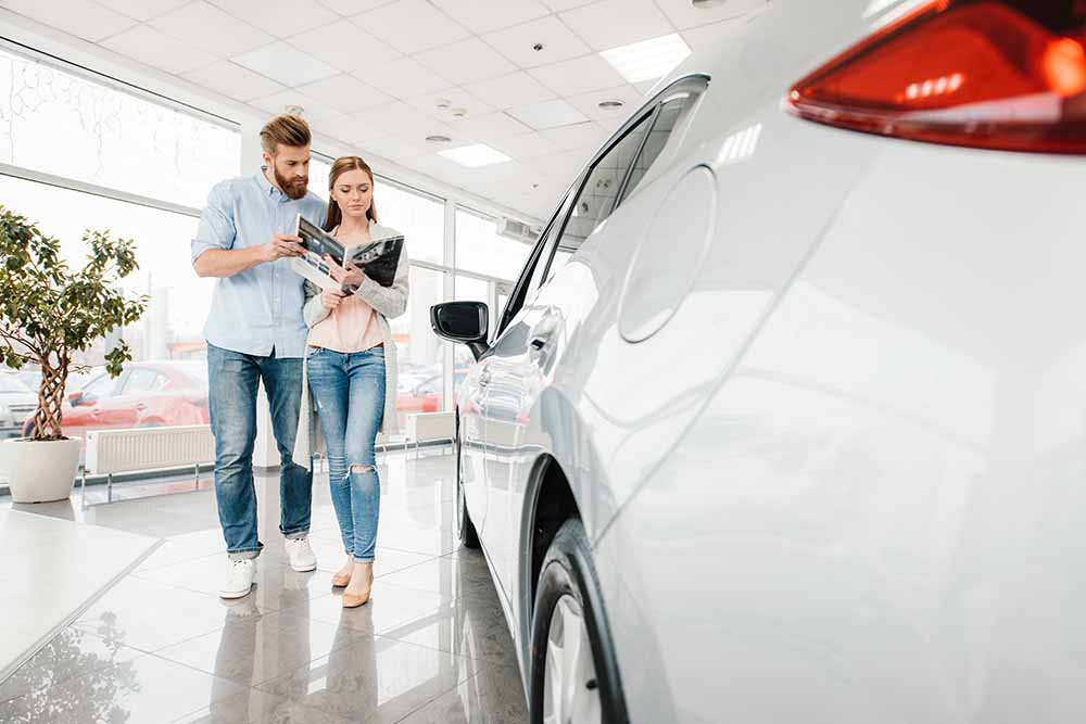 Couple looking at a catalogue in a car dealership