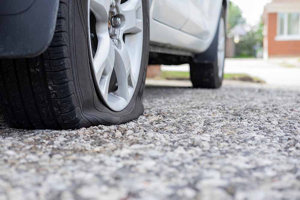 Car with a flat tire parked in a driveway