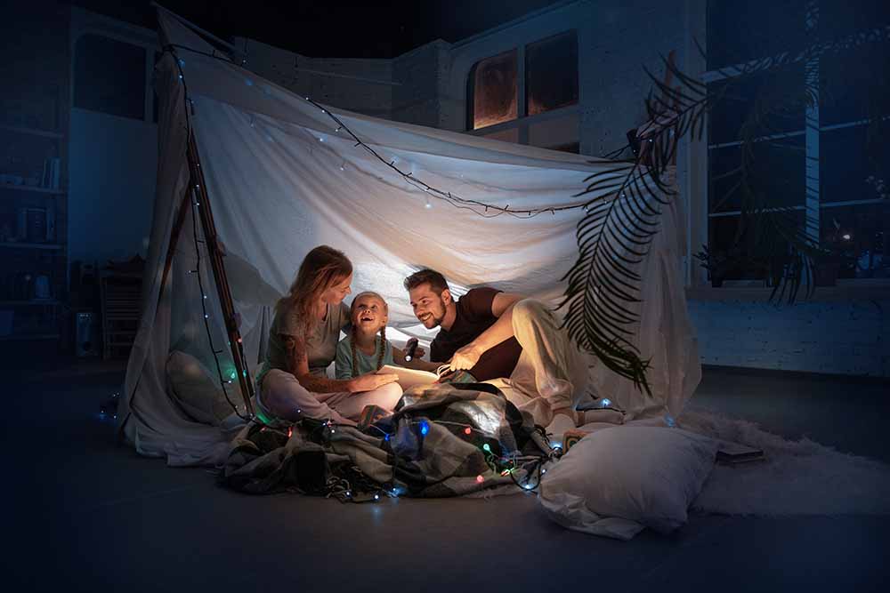 Young family sitting inside a blanket fort