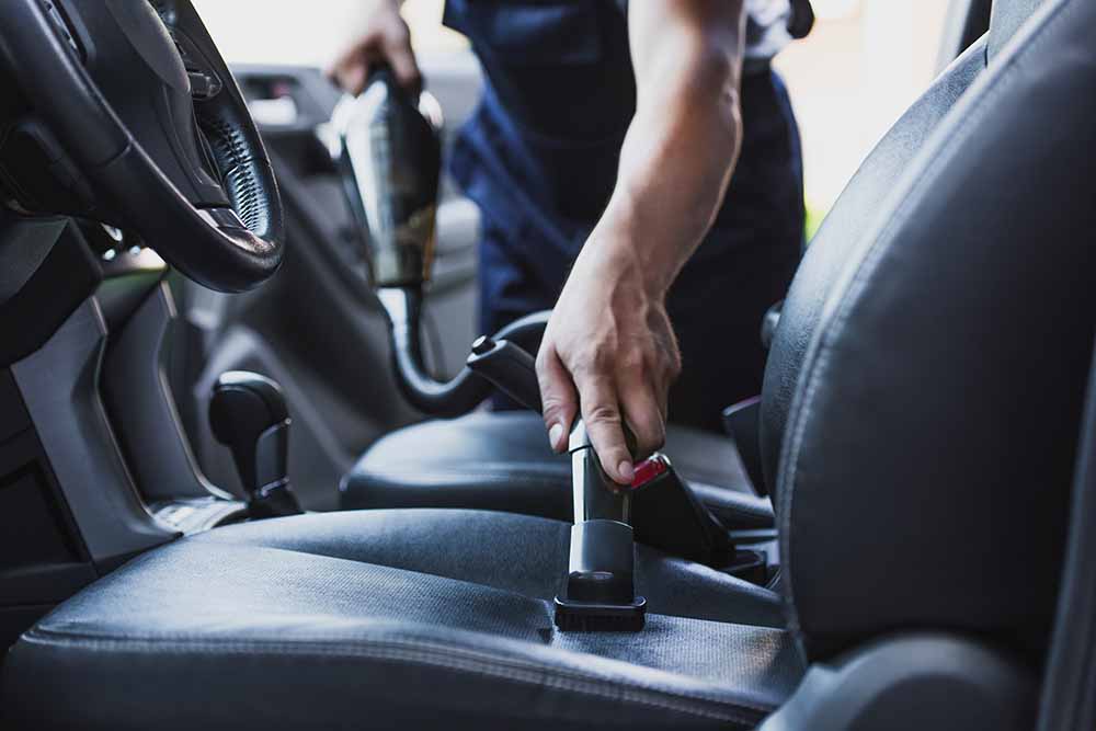 Une personne qui passe l’aspirateur à l’intérieur d’une voiture